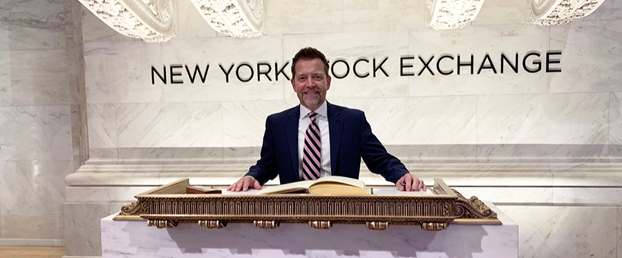 Kelly Baltes at a podium in the New York Stock Exchange
