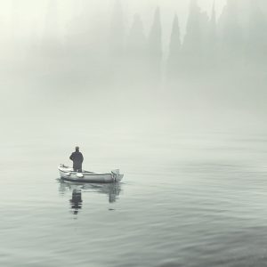 Fisherman on foggy lake