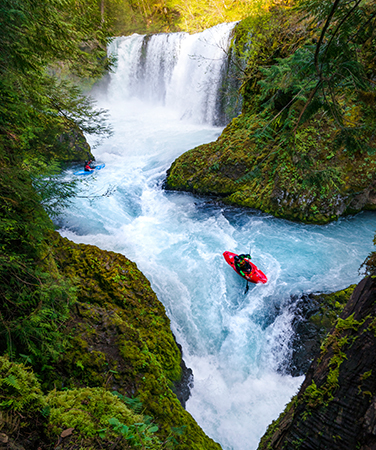 Kayaker navigating rapids and waterfall