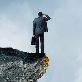 Businessman standing on cliff looking into the distance